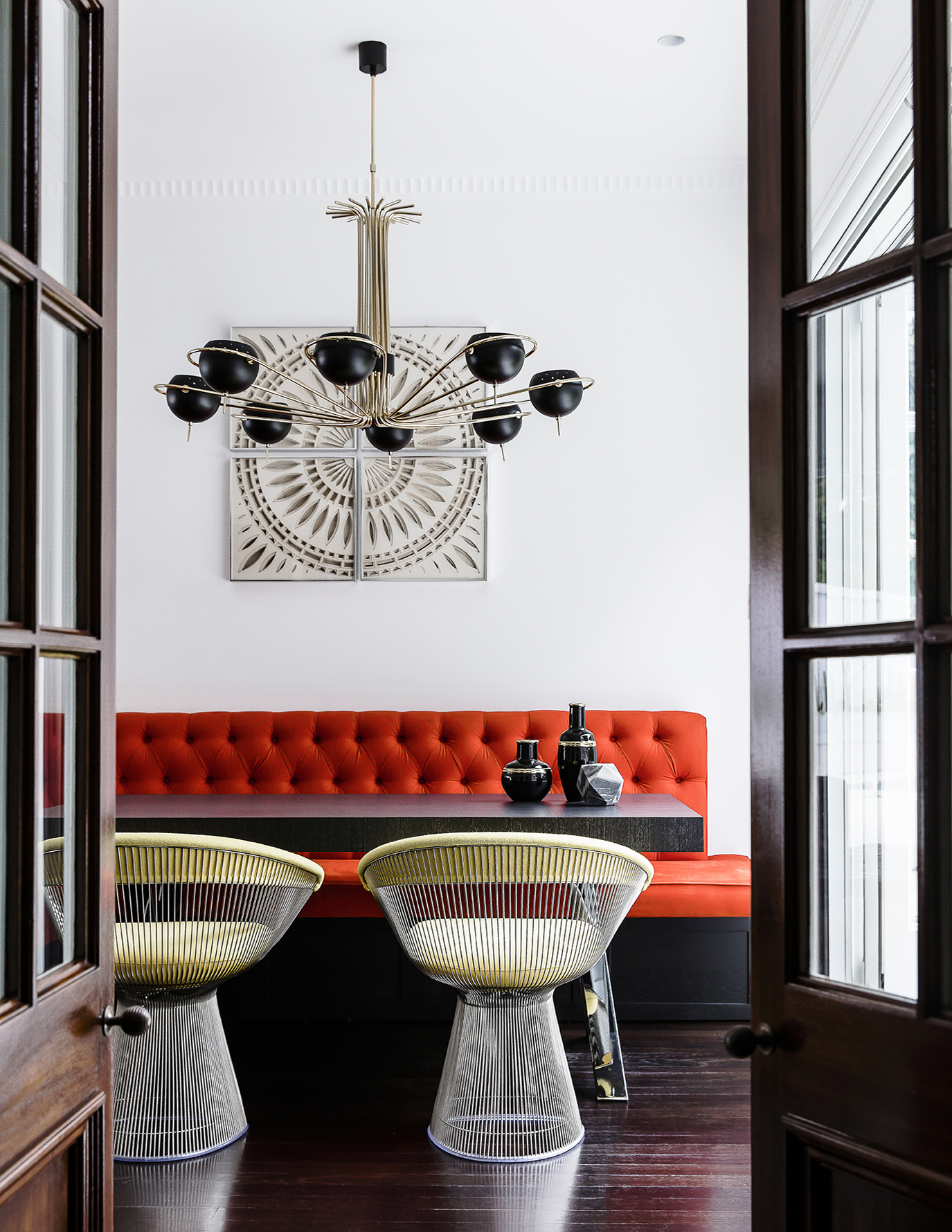 Casual dining room with tufted banquette booth seating in orange and Knoll Platner chairs, by Sydney interior designers