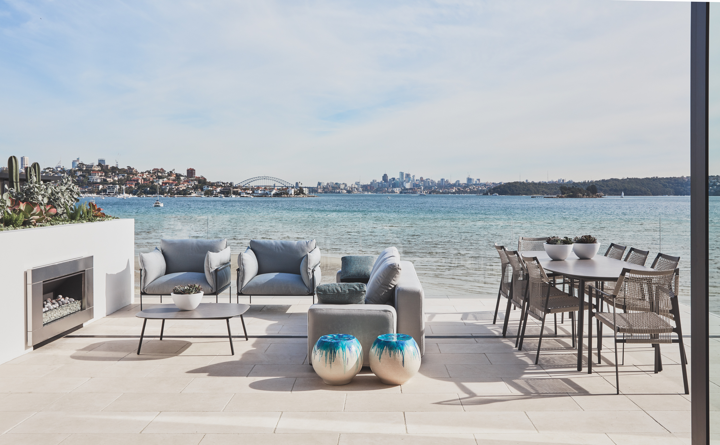 Rose Bay beach penthouse balcony with outdoor fireplace and dining furniture by Sydney interior designers Brendan Wong Design
