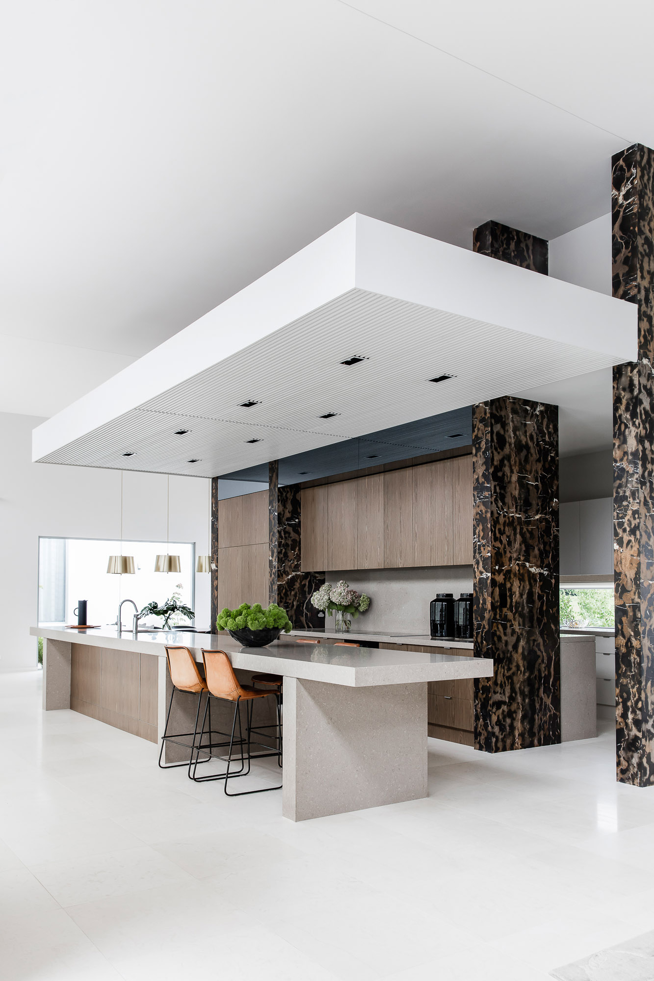 Tall double-height kitchen with bold black and gold marble, Caesarstone benchtop and timber doors by Sydney interior designer