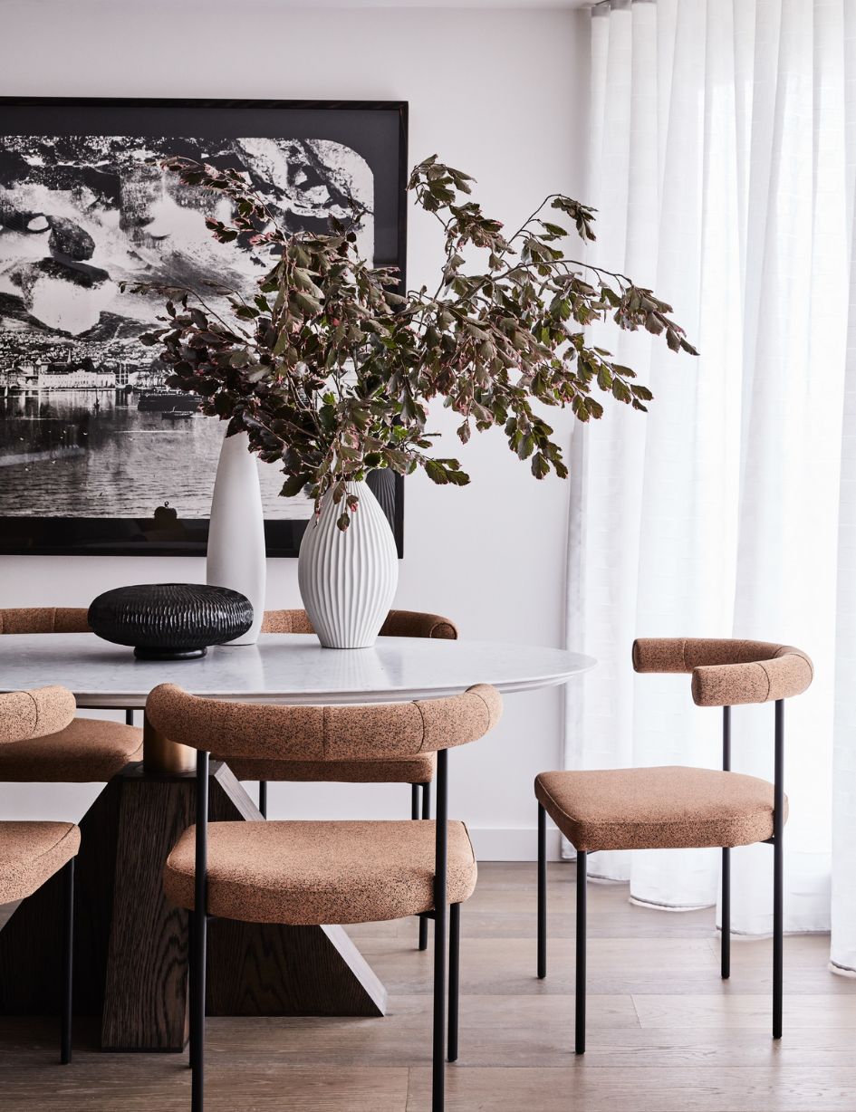 Elegant dining area at Collectors Retreat Apartment by Brendan Wong Design, featuring a marble-topped table, sculptural timber base, contemporary upholstered chairs, and curated decorative vases.