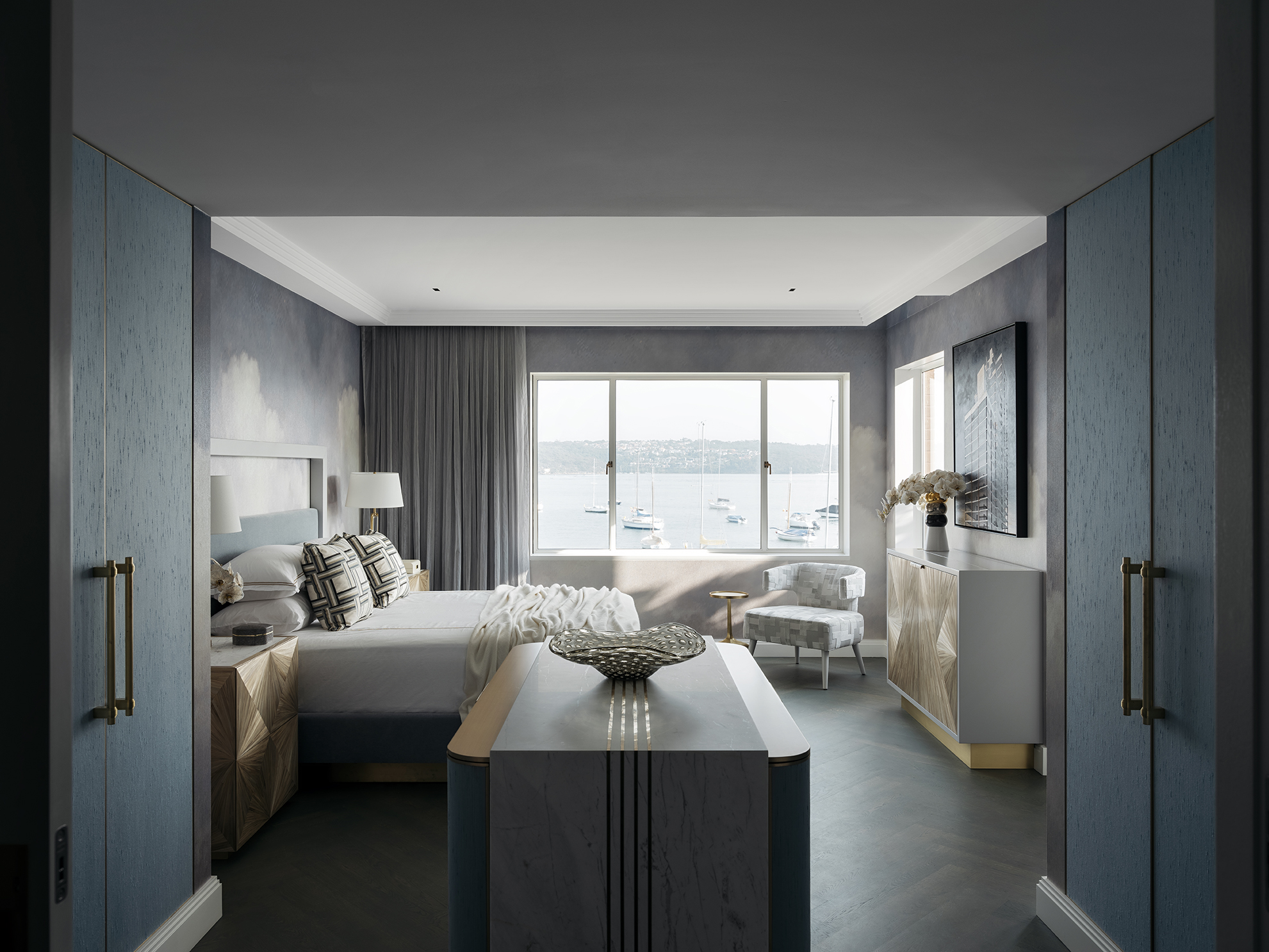Elegant waterfront bedroom featuring cloud-mural wallpaper, custom joinery, and a serene, light-filled palette, styled by Brendan Wong Design in Point Piper.