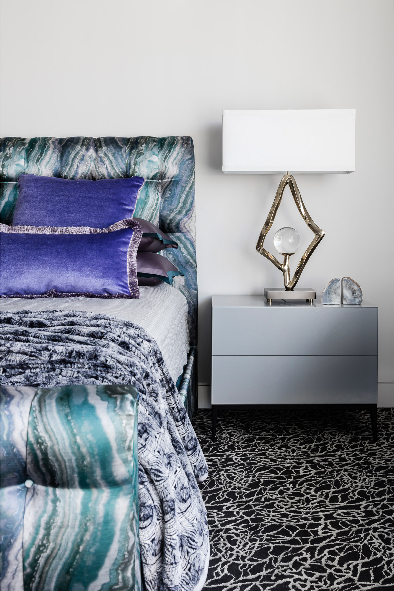 Chic penthouse bedroom with jewel-toned silk bedhead, metallic lighting, and richly textured textiles, designed by Brendan Wong Design overlooking Sydney Harbour.